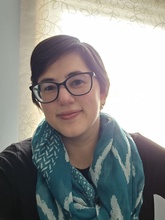 Woman with short hair and wearing a blue scarf.