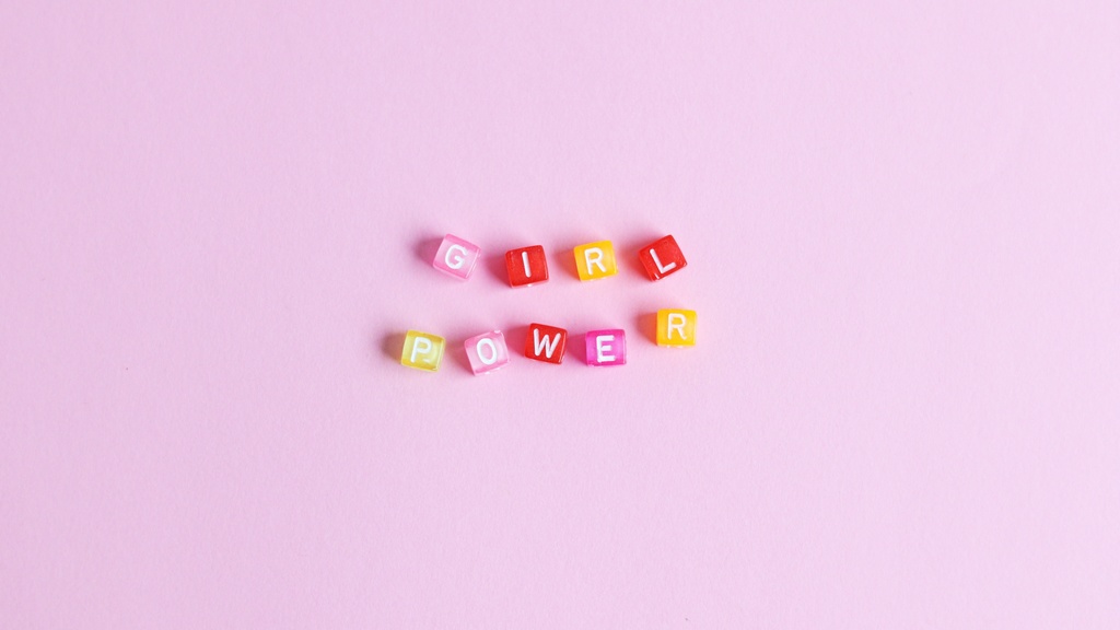 Pink, yellow and red blocks that spell "girl power" on a pink background.