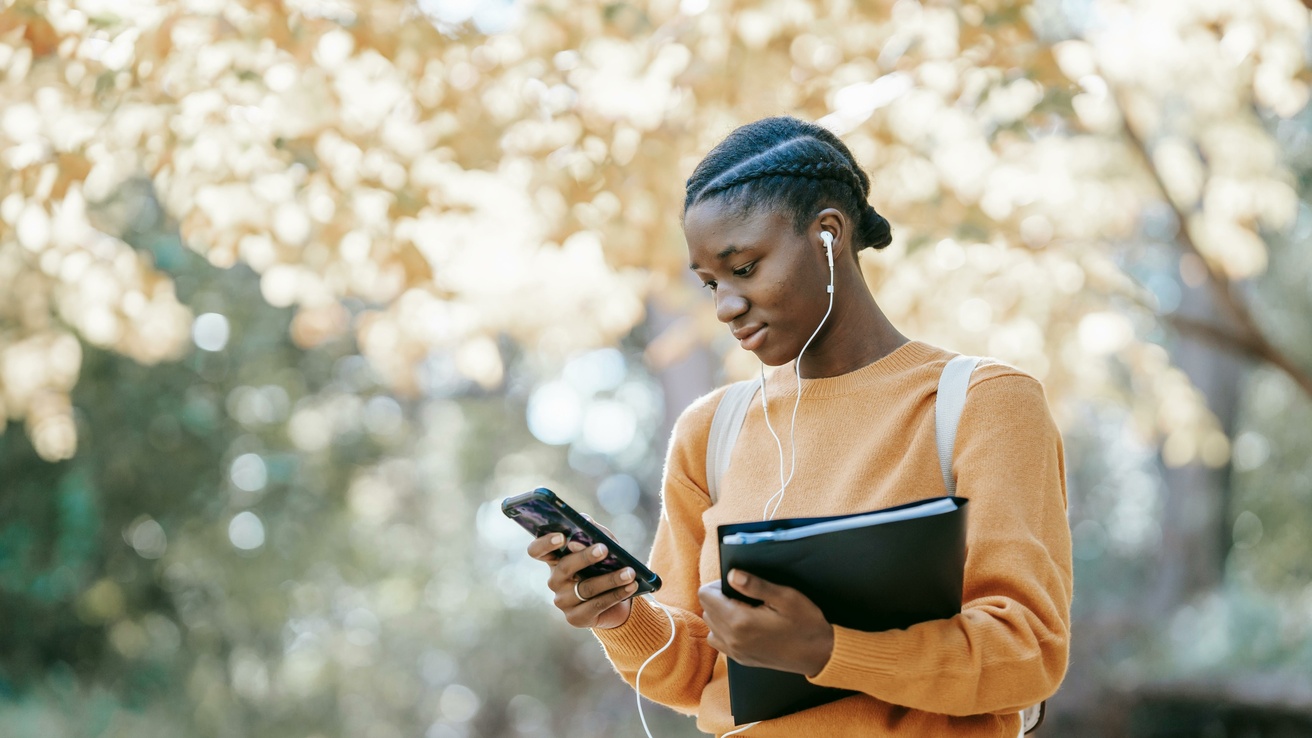 woman looking at phone while listening to something with earphones